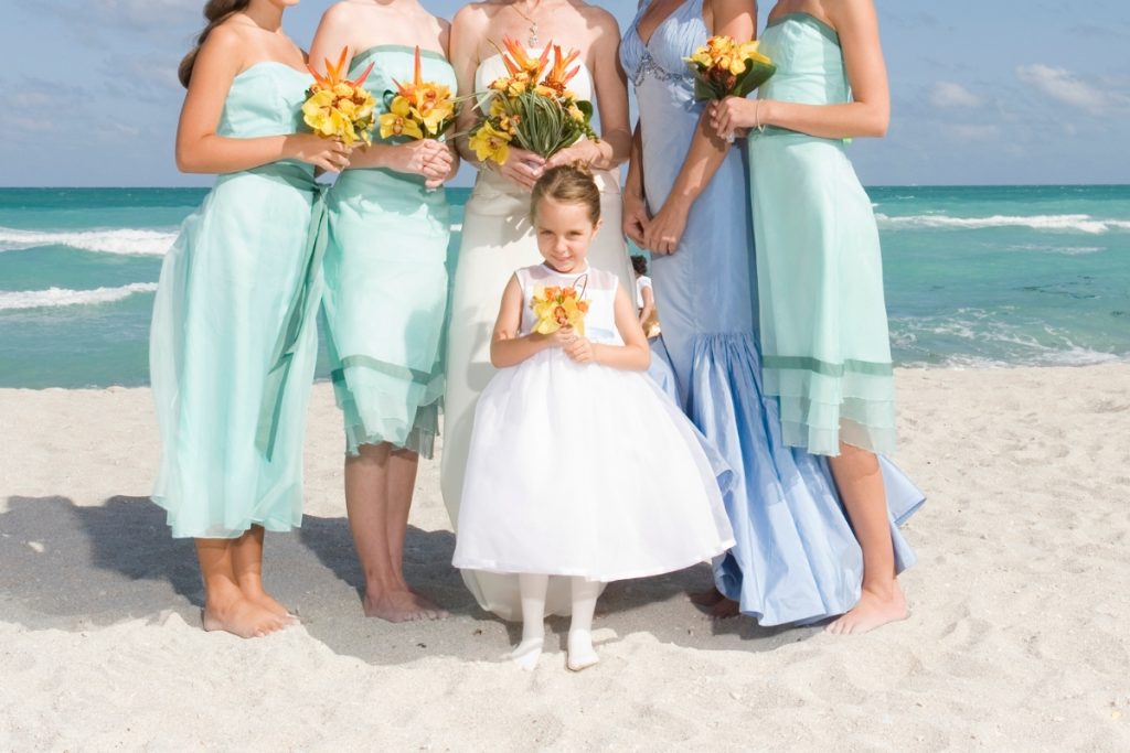 Bridal party posing with the flower girl during a tropical destination wedding celebration.