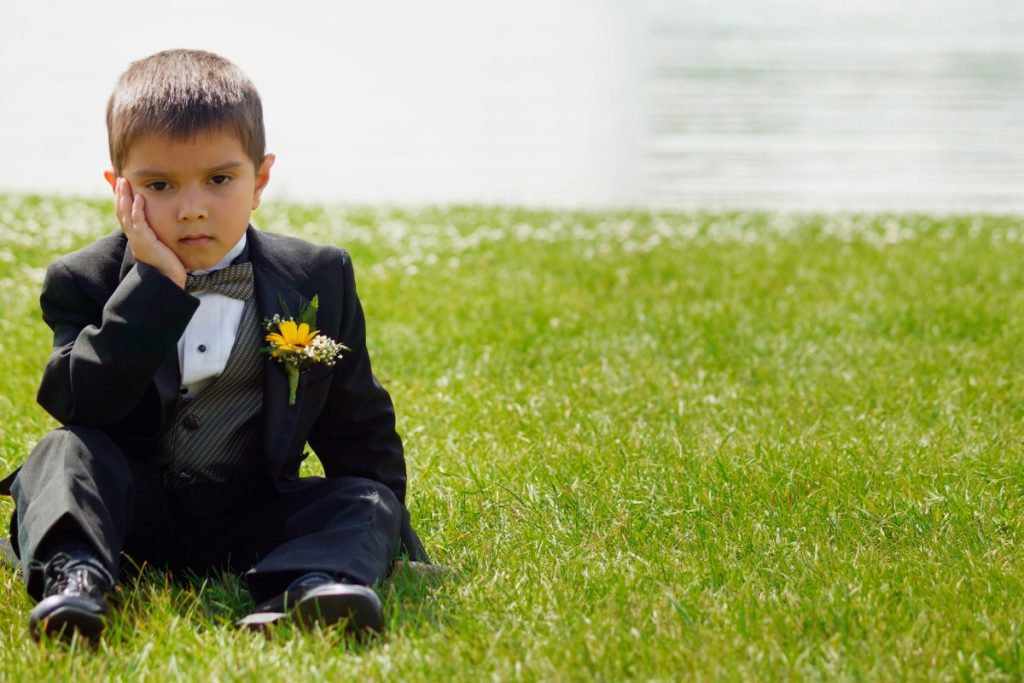 Young child looking tired during an outdoor tropical destination wedding ceremony.
